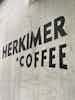 A cement wall with bold, black lettering in all caps reading "Herkimer Coffee" with a little black star.